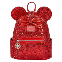 A red sequined mini backpack featuring Minnie Mouse ears, a large shiny red bow, and a silver snowflake charm, shown on a plain white background.