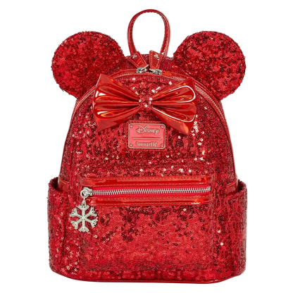 A red sequined mini backpack featuring Minnie Mouse ears, a large shiny red bow, and a silver snowflake charm, shown on a plain white background.