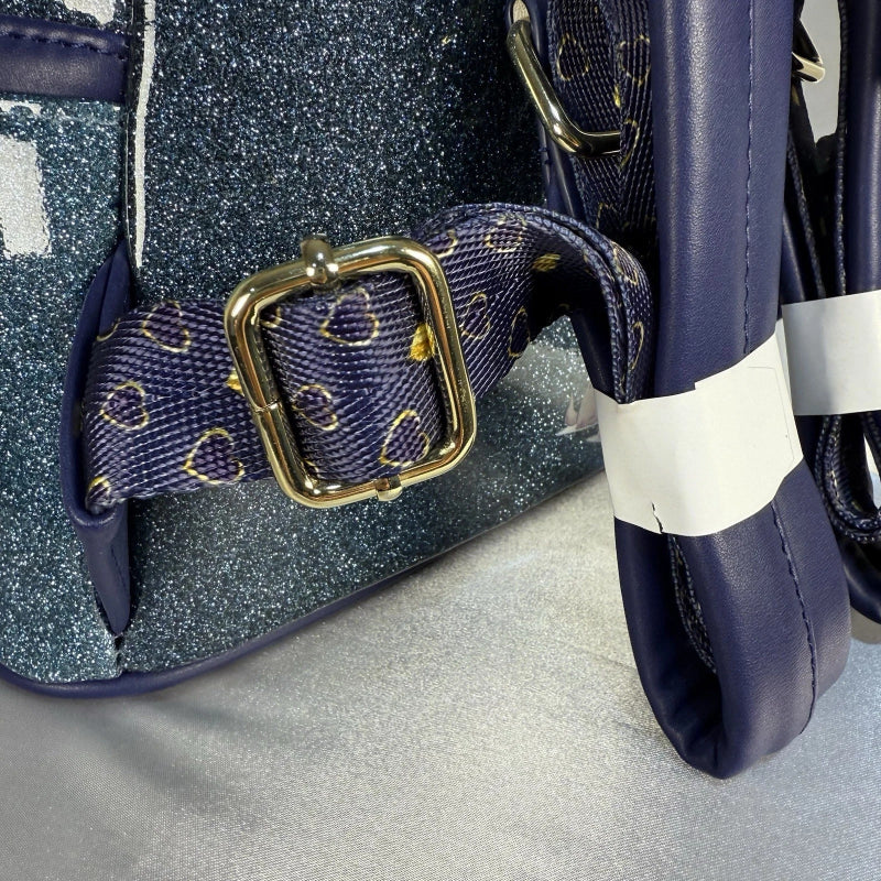 Close-up of a blue glittery handbag with a gold buckle on a gray surface