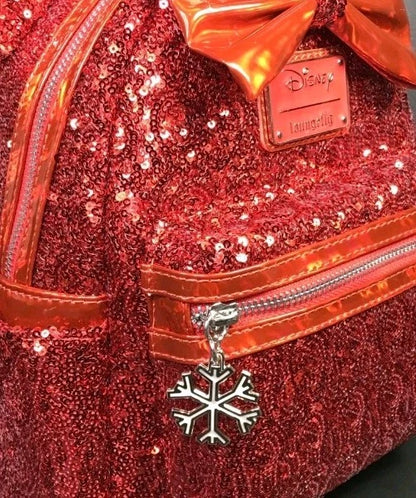Close-up of a red sequined Disney Loungefly bag with a metallic copper bow, silver zipper, and a silver snowflake charm.