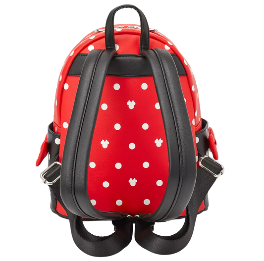 Red and white polka dot backpack with black faux-leather straps and silver buckles, shown from the back on a white background.